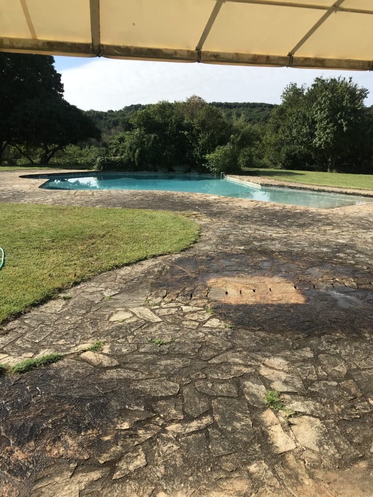 Terrasse en pierres naturelles noircies et encrassées autour d'une piscine avant rénovation à Sens